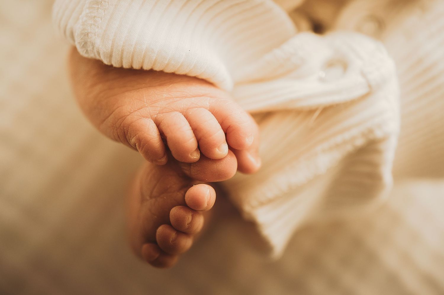 Close-up of tiny baby feet wrapped in white knit blanket.