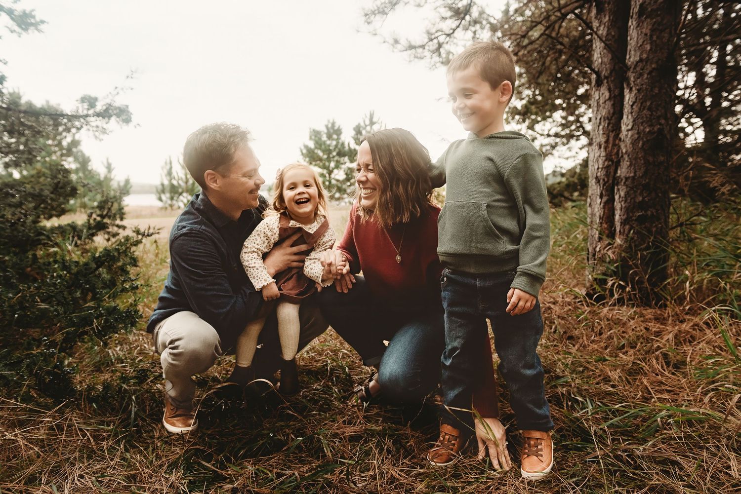 People sitting together on fallen leaves in a wooded outdoor setting.